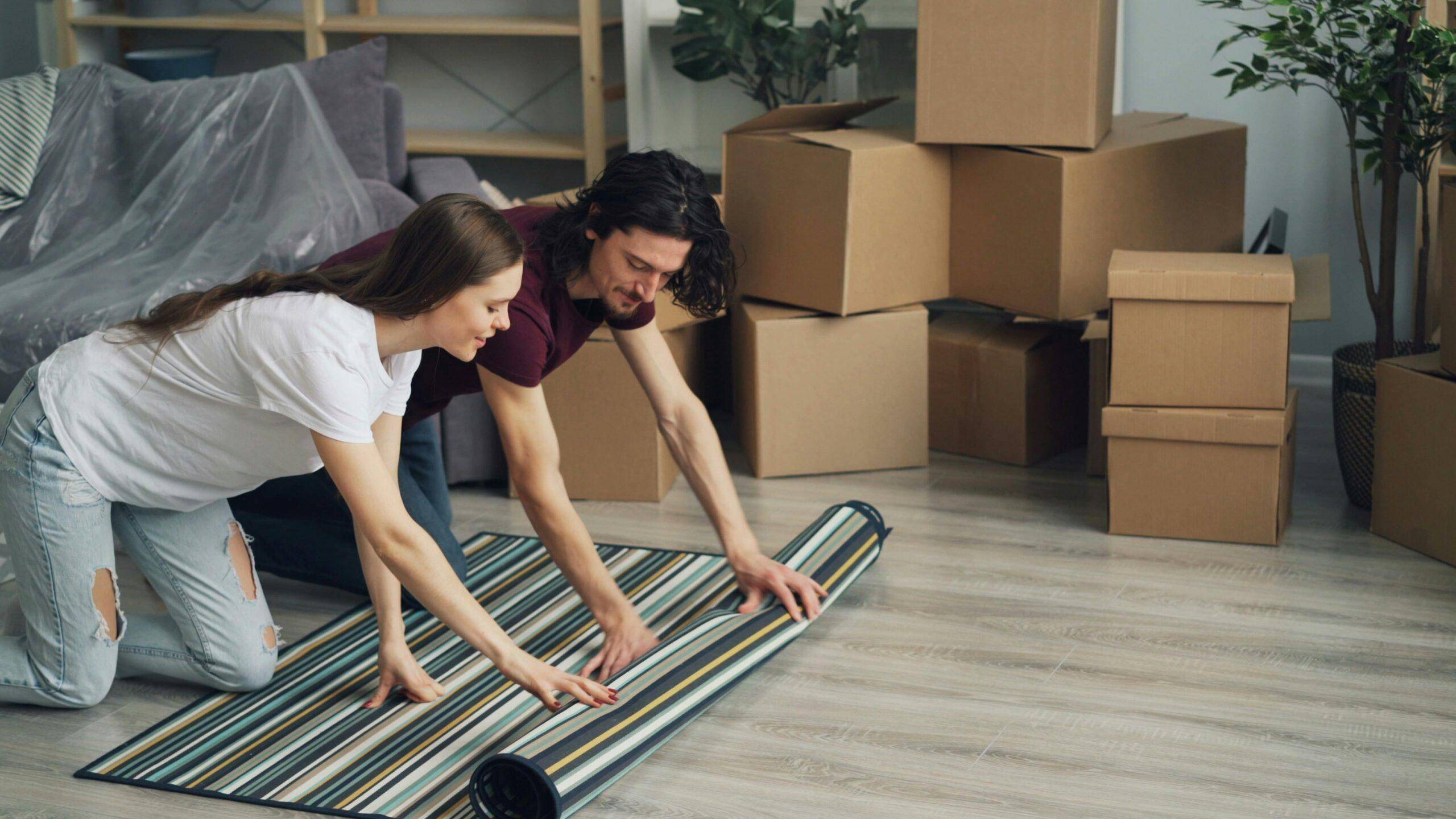 Young couple unrolling a rug in their new home